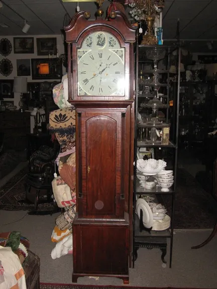 English Tall Case Clock. Late 18th Century, mahogany. Eight-day brass movement with calendar. Original hands and painted dial. Shot filled weights. Case with reeded quarter columns. Bonnet topped with broken arched pediment with brass rosettes, center with brass eagle finial.