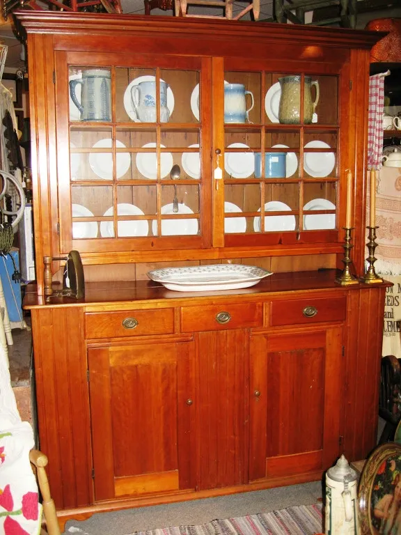 Cherry two-piece eighteen-pane dish cupboard, top consisting of two multi-pane doors, molded cornice, pie shelf, base consisting of three hand-dovetailed drawers over two paneled doors, bracket base.